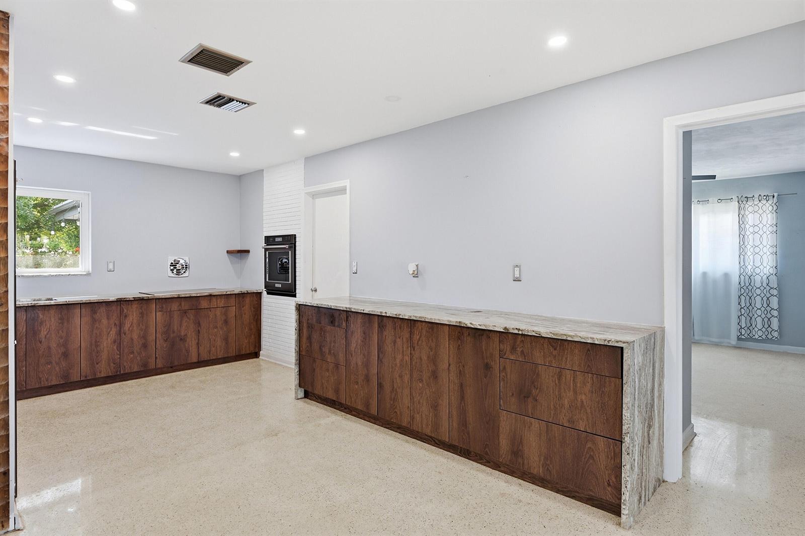 A kitchen features dark wood cabinets, granite countertops, and light gray walls — 370 SW 13th Street, Pompano Beach FL 33060, POMPANO BEACH, FL