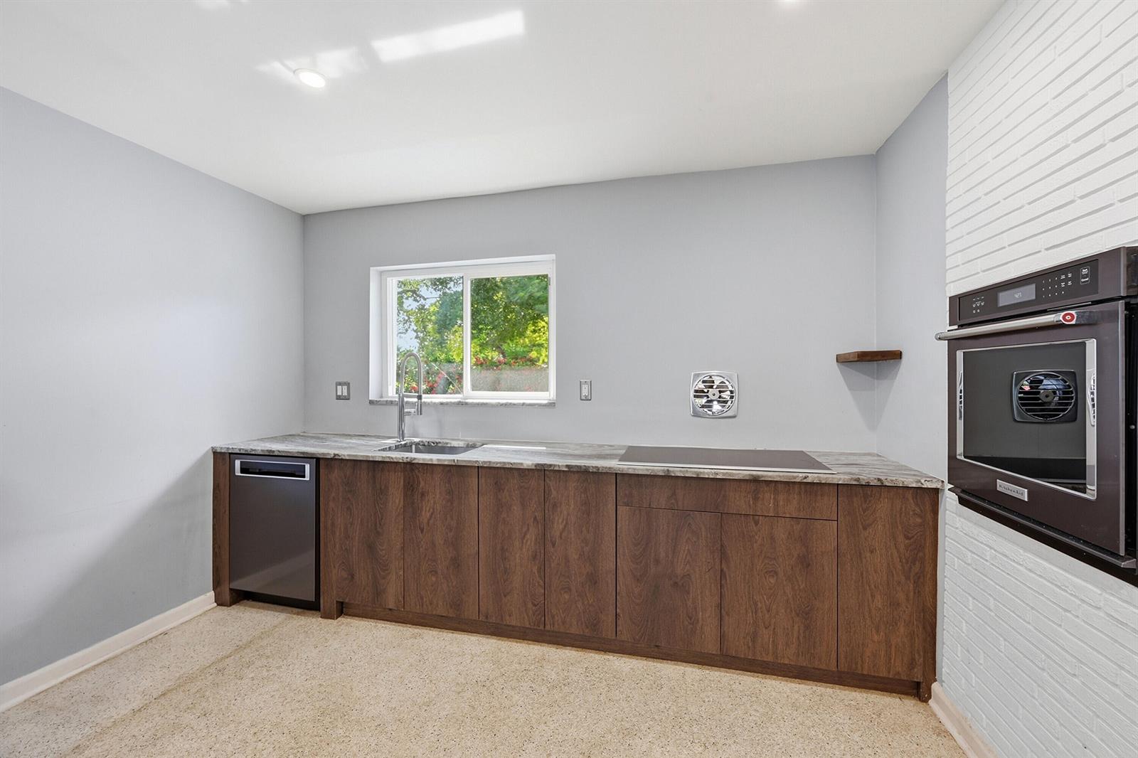 A kitchen features dark wood cabinets, a stone countertop, a dishwasher, and a wall oven — 370 SW 13th Street, Pompano Beach FL 33060, POMPANO BEACH, FL