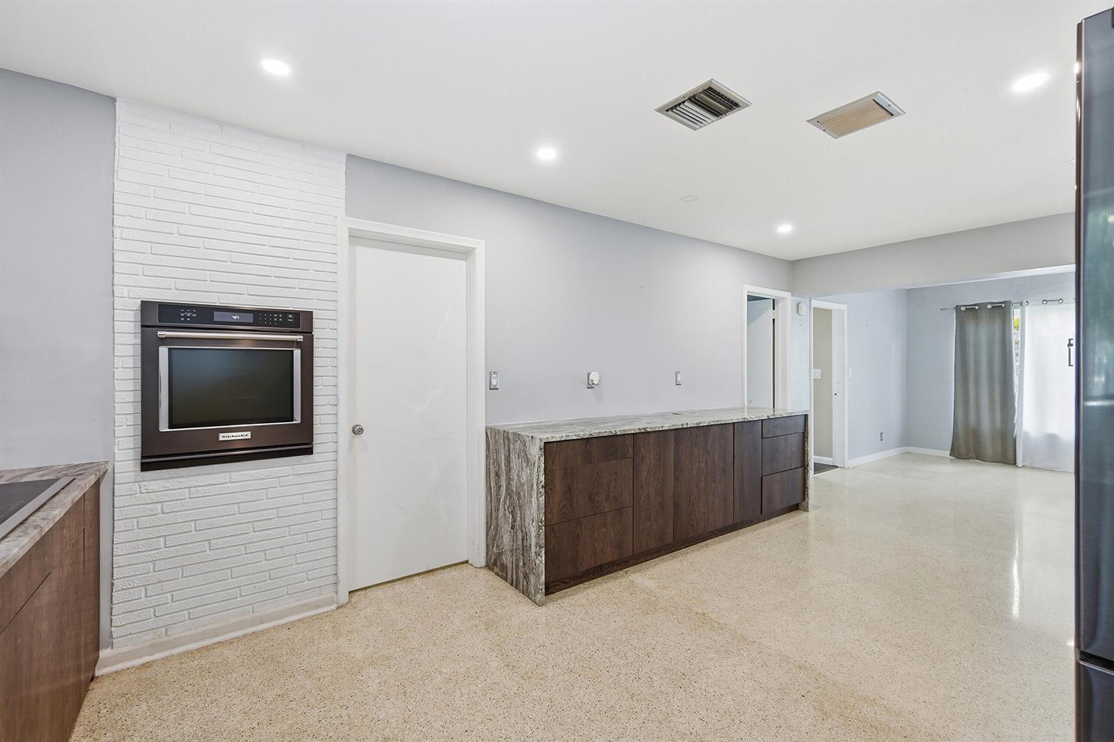 A kitchen features dark wood cabinets, a stone countertop, a built-in oven, and white brick — 370 SW 13th Street, Pompano Beach FL 33060, POMPANO BEACH, FL
