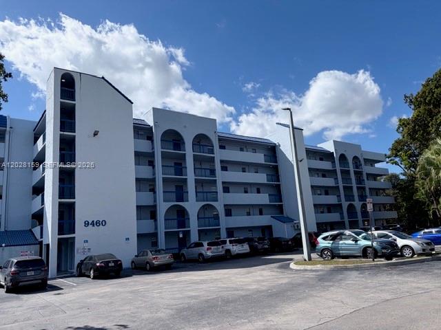 A multi-story apartment building features arched balconies and a parking lot in the foreground — 9460 Fontainebleau Blvd # 529, Miami FL 33172, MIAMI, FL