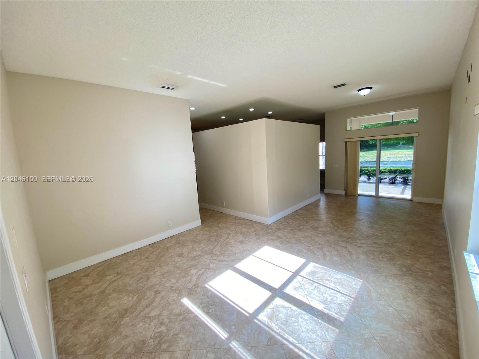 An open-concept living area features beige walls, tile flooring, and a sliding glass door — 837 Tanglewood Cir, Weston FL 33327, WESTON, FL