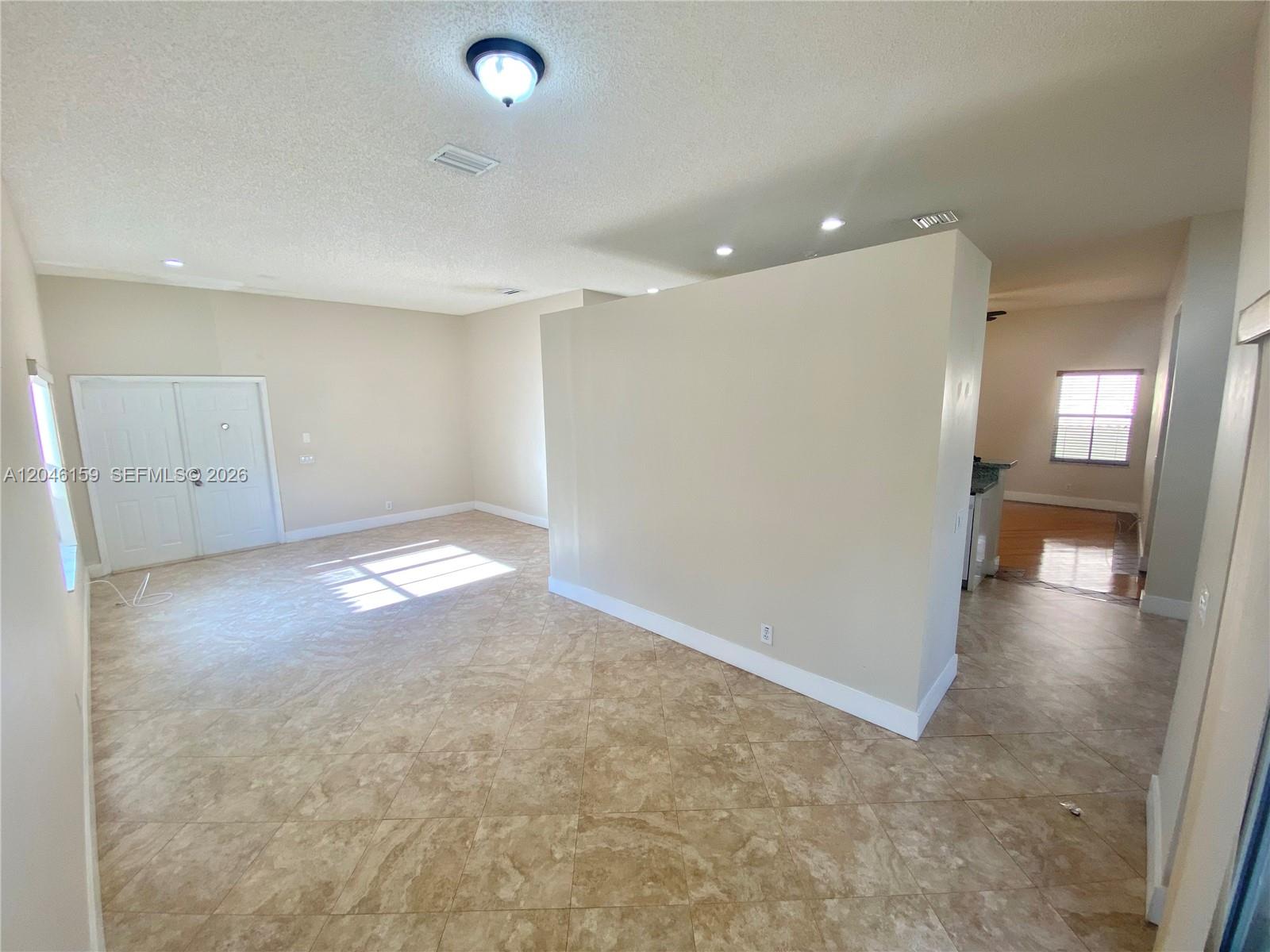 An open-concept room features beige walls, light-colored tile flooring, and a central partition wall — 837 Tanglewood Cir, Weston FL 33327, WESTON, FL