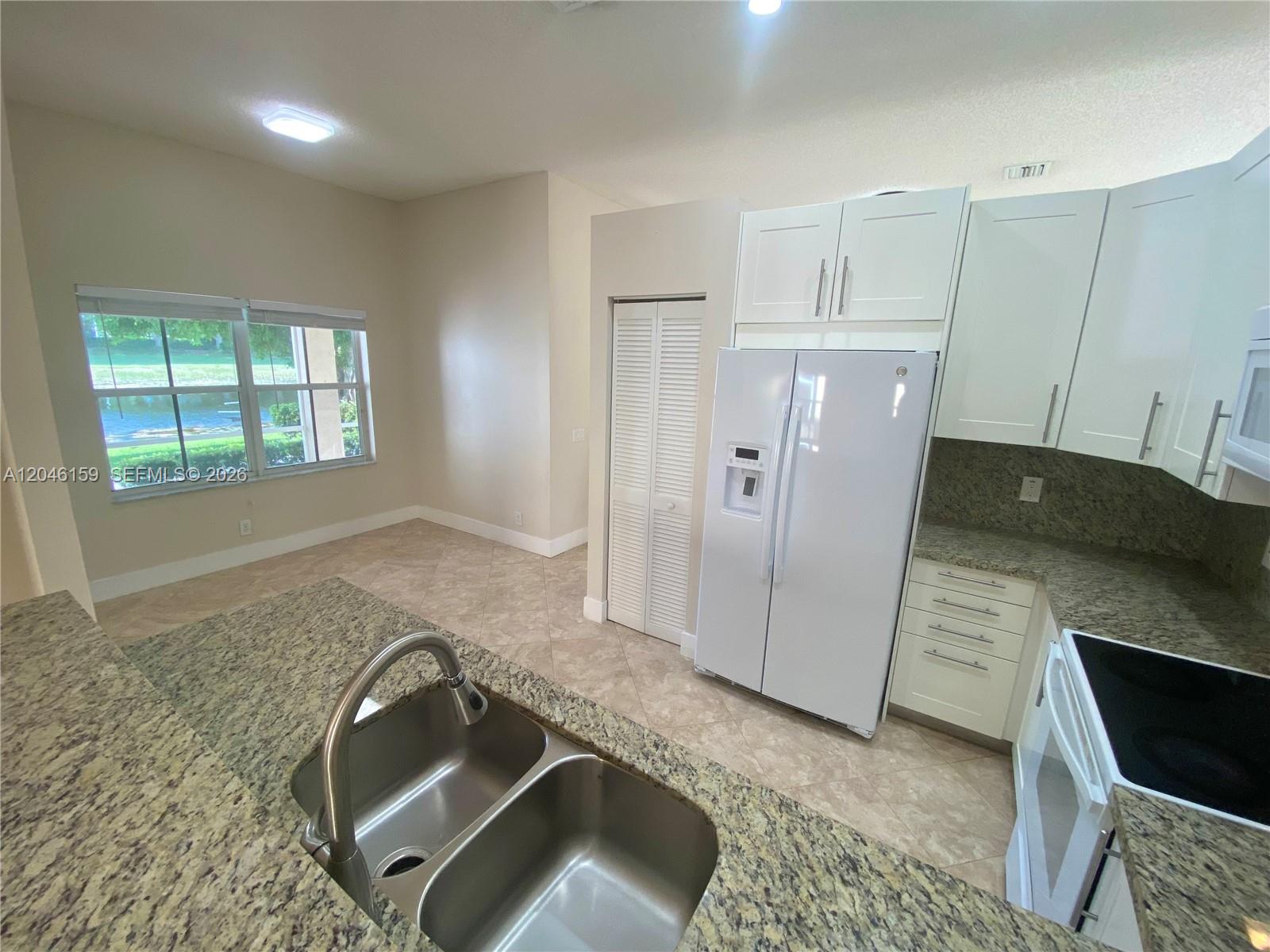 A kitchen features white cabinets, granite countertops, a stainless steel sink, and a view outside — 837 Tanglewood Cir, Weston FL 33327, WESTON, FL