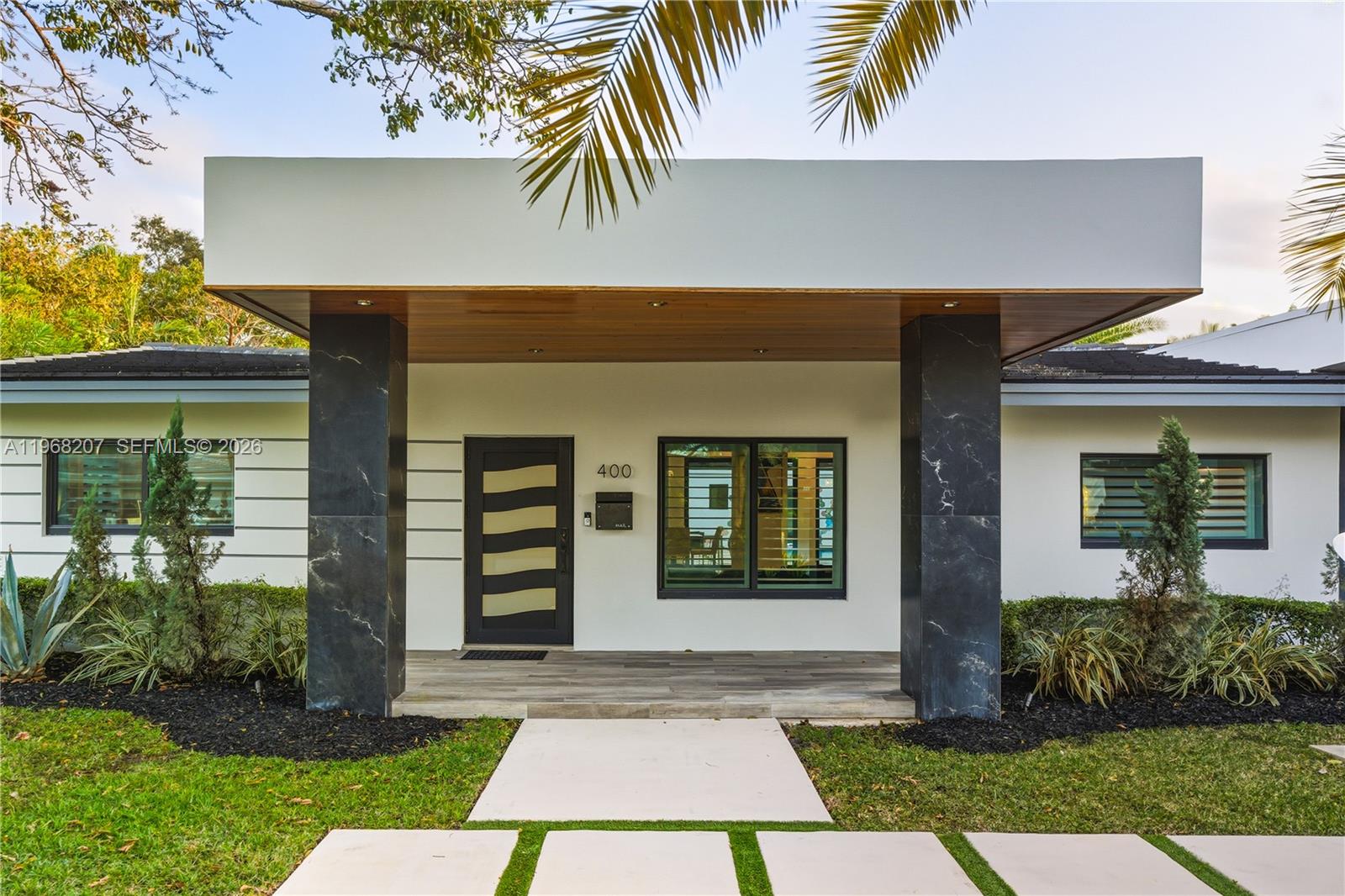 A backyard features a rectangular swimming pool, patio furniture, and a palm tree at dusk — 400 NW 24th St, Wilton Manors FL 33311, WILTON MANORS, FL