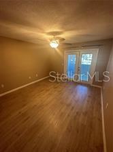 An empty room with light wood-look flooring, a ceiling fan, and glass doors leading outside — 904 LAKE DESTINY ROAD UNIT H, ALTAMONTE SPRINGS, FL