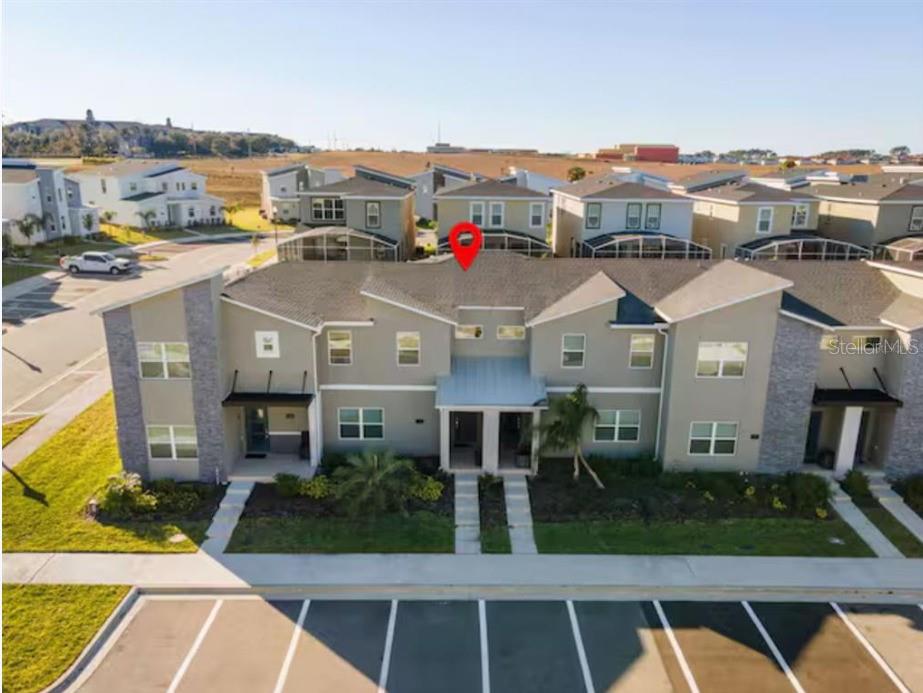 An aerial view of a multi-unit townhouse building with a parking lot in the foreground — 1184 KINGSBARN STREET, DAVENPORT, FL