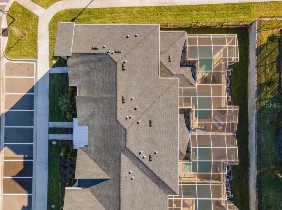 An aerial view shows the shingled roof of a multi-unit building with screened-in pool enclosures — 1184 KINGSBARN STREET, DAVENPORT, FL
