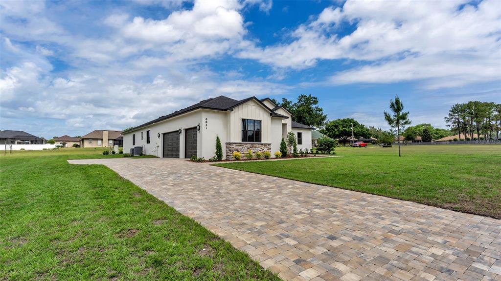 A modern single-story house with a paver driveway, two-car garage, and stone accents — 6827 LAKELAND HIGHLANDS ROAD, LAKELAND, FL