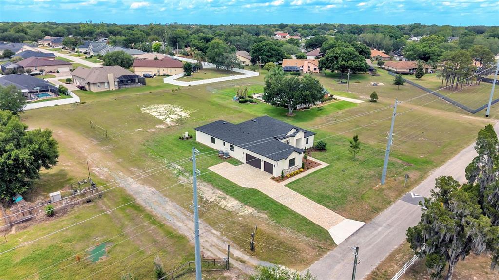 An aerial view shows a single-story house with a dark roof and a paved driveway — 6827 LAKELAND HIGHLANDS ROAD, LAKELAND, FL