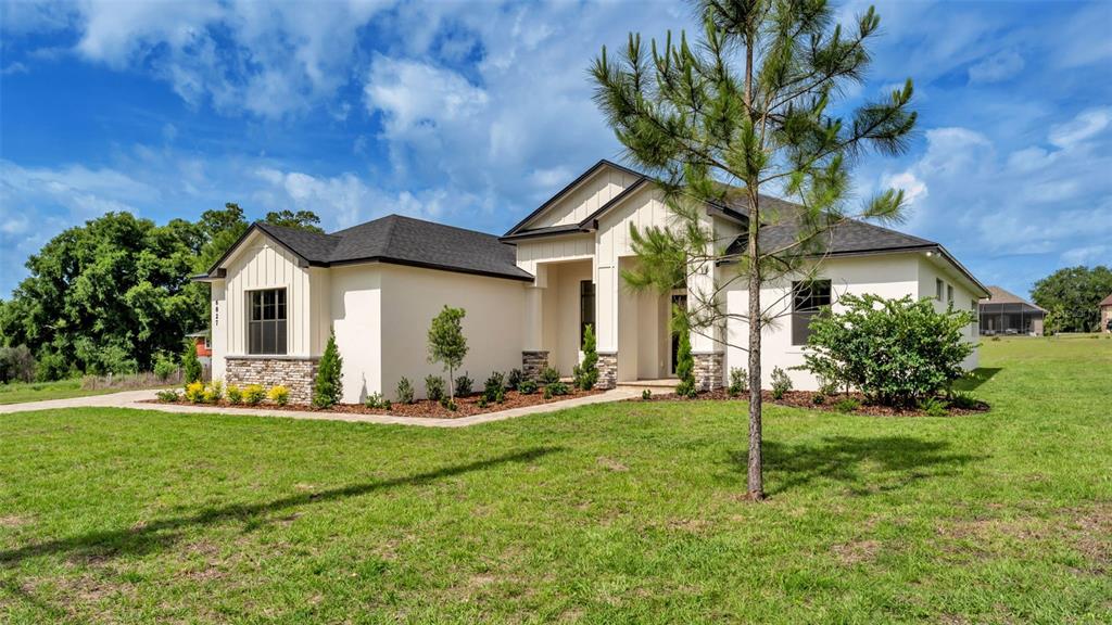 A modern single-story house with white stucco siding, stone accents, and a dark shingled roof — 6827 LAKELAND HIGHLANDS ROAD, LAKELAND, FL