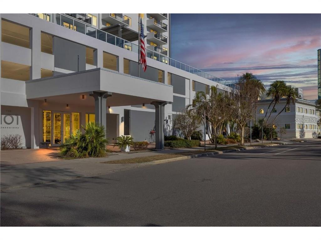 The exterior of a multi-story condominium building features a covered entrance with a flag — 101 S GULFSTREAM AVENUE UNIT 10B, SARASOTA, FL