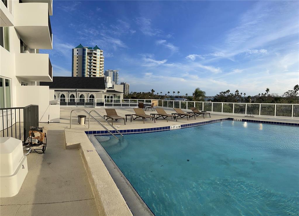 An outdoor swimming pool with lounge chairs on a deck overlooking a city skyline — 101 S GULFSTREAM AVENUE UNIT 10B, SARASOTA, FL