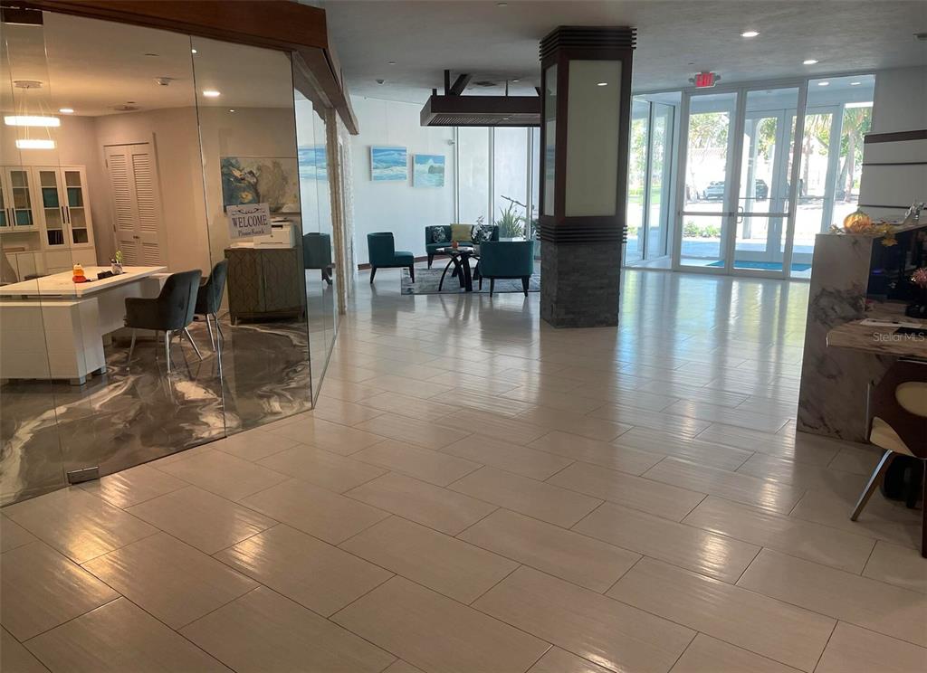 A bright lobby features tiled floors, a glass-enclosed office, and a central seating area — 101 S GULFSTREAM AVENUE UNIT 10B, SARASOTA, FL