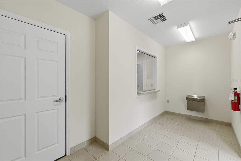 A room with white walls, tile flooring, a door, a service window, and a water fountain — 4370 NE 35TH STREET UNIT 2, OCALA, FL