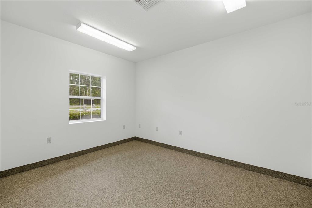 An empty room with white walls, beige carpeting, a single window, and fluorescent lighting — 4370 NE 35TH STREET UNIT 2, OCALA, FL