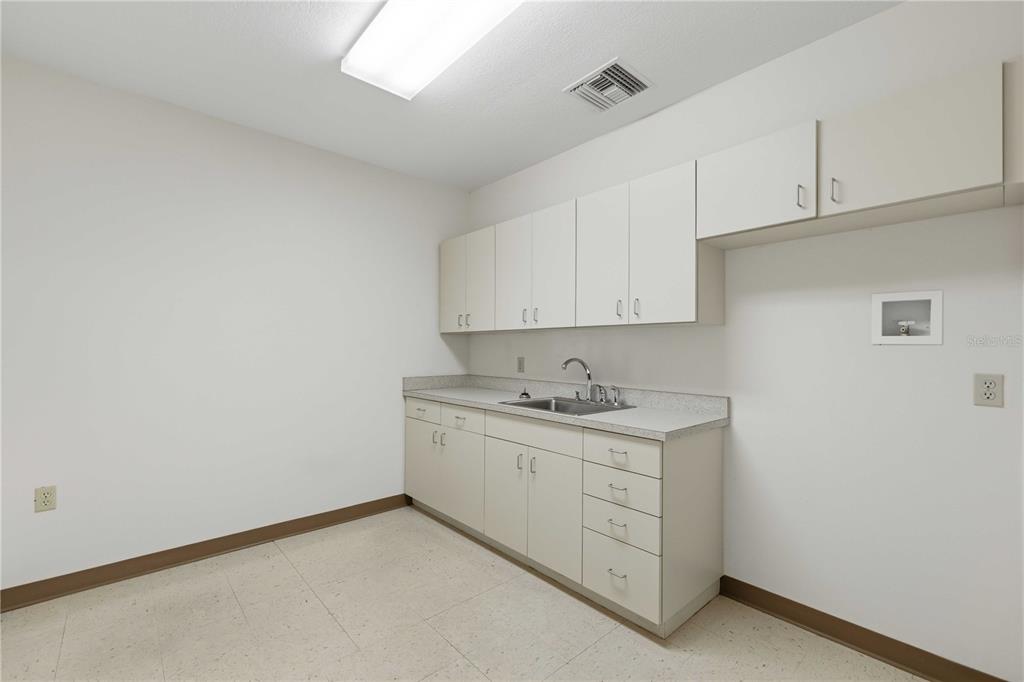 A utility room features white cabinets, a stainless steel sink, and light-colored vinyl flooring — 4370 NE 35TH STREET UNIT 2, OCALA, FL