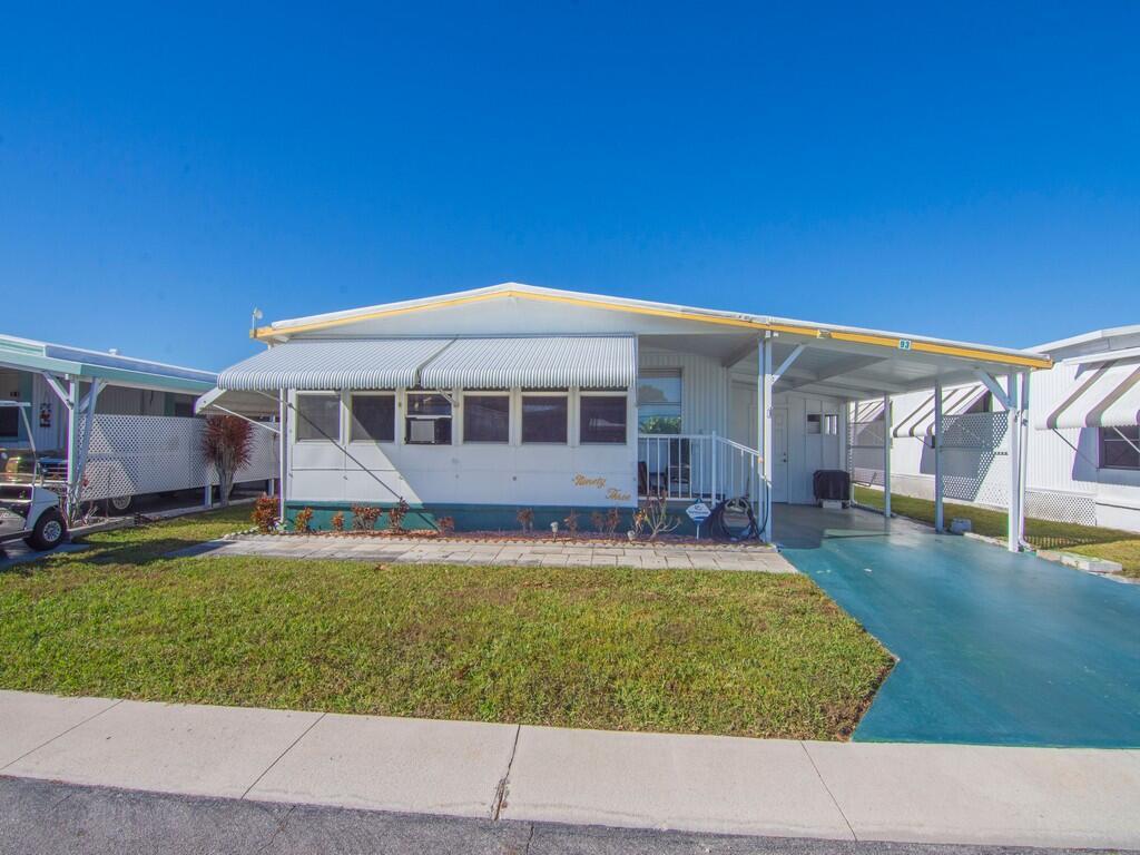 A single-story mobile home with a white exterior, metal awnings, and an attached carport — 4800 SE Federal Highway # 93, Stuart FL 34997, STUART, FL