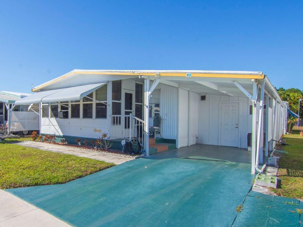 A white mobile home with a green driveway, a carport, and a screened-in front porch — 4800 SE Federal Highway # 93, Stuart FL 34997, STUART, FL