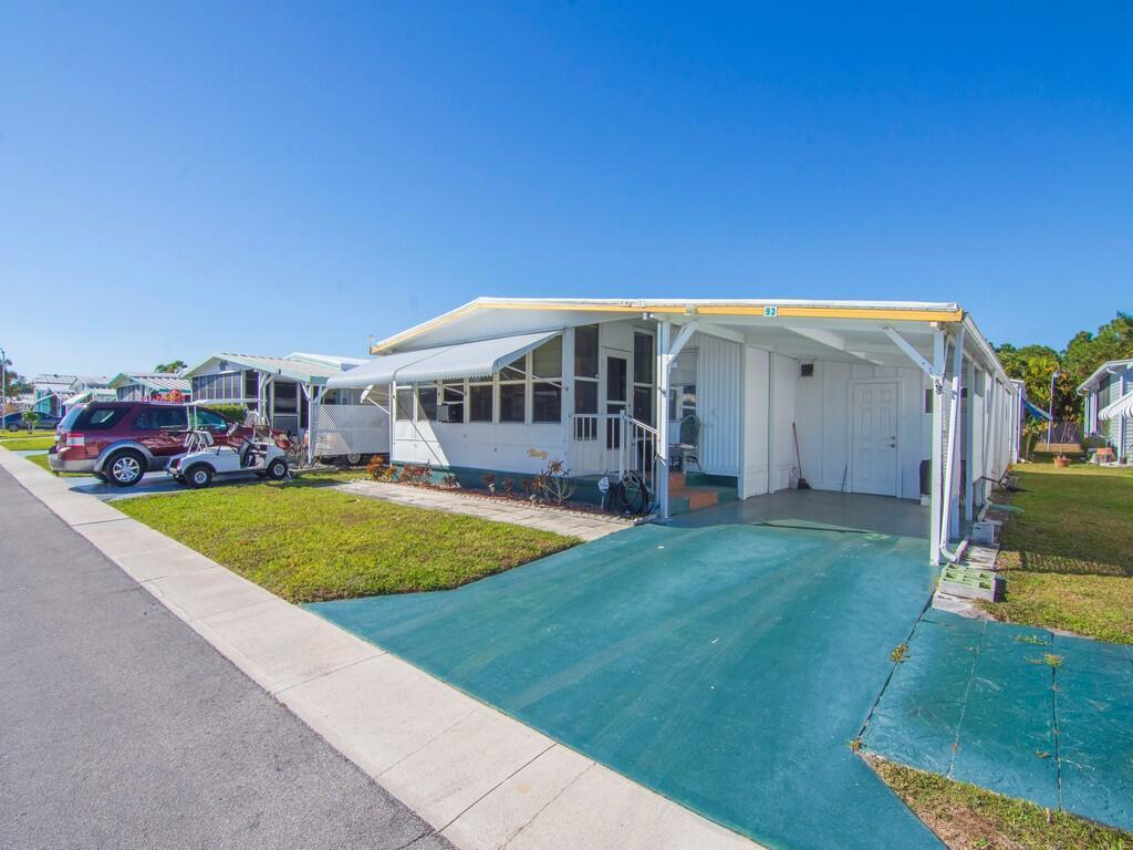 A mobile home with a green driveway, a carport, and a small golf cart parked outside — 4800 SE Federal Highway # 93, Stuart FL 34997, STUART, FL