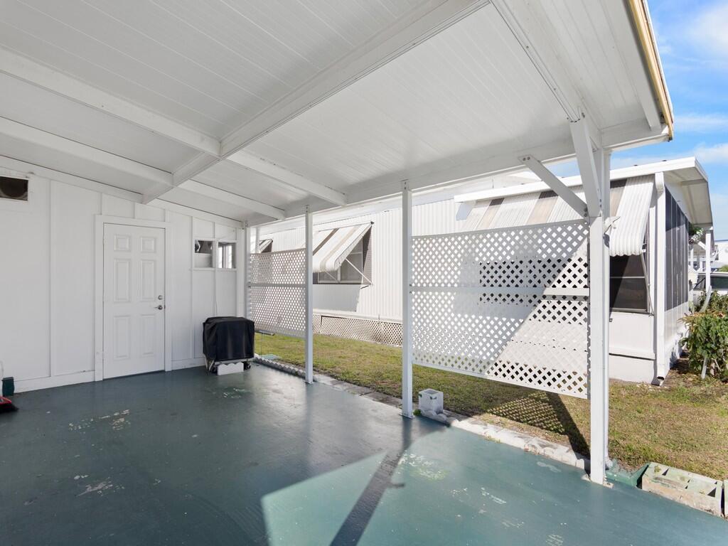 A covered patio with a painted concrete floor, white lattice privacy screens, and a door — 4800 SE Federal Highway # 93, Stuart FL 34997, STUART, FL