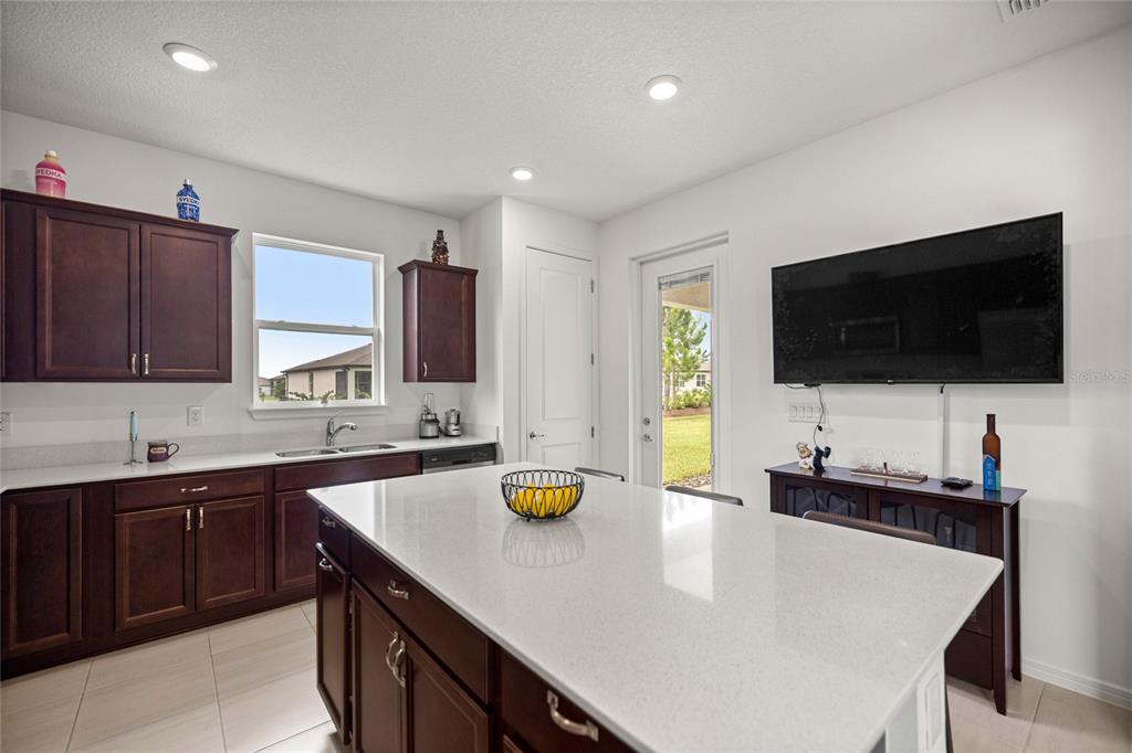 A kitchen features dark wood cabinets, white countertops, a central island, and a wall-mounted television — 9412 SW 53RD PLACE, OCALA, FL