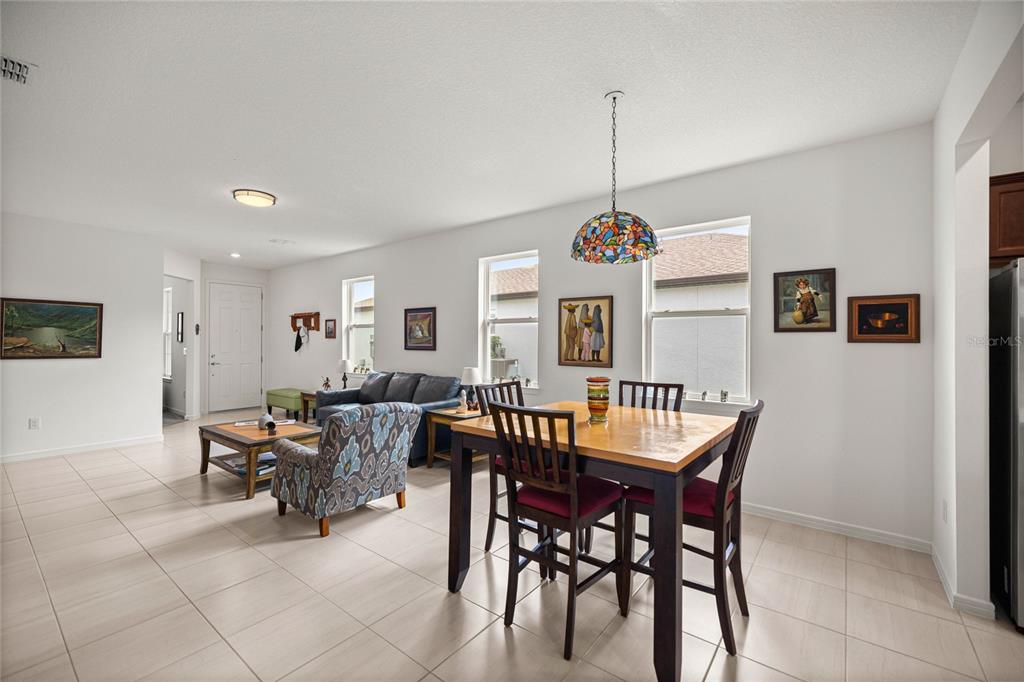 An open-concept living and dining area features tile flooring, white walls, and a stained-glass pendant — 9412 SW 53RD PLACE, OCALA, FL