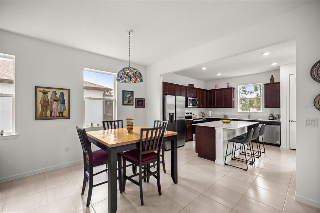 A dining area with a wooden table and chairs opens into a kitchen with island seating — 9412 SW 53RD PLACE, OCALA, FL