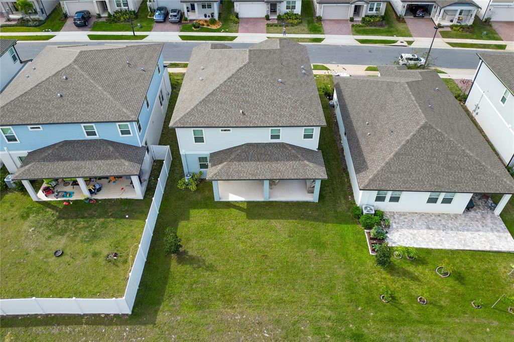 An aerial view shows the backyards and rear exteriors of three suburban houses — 2284 BEAR PEAK ROAD, CLERMONT, FL