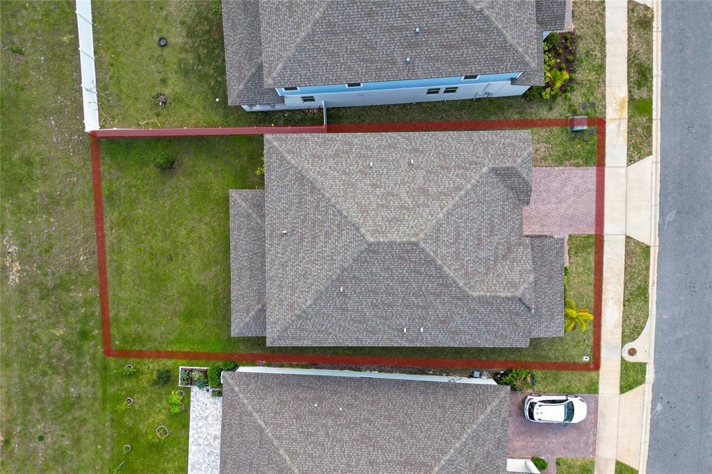 An aerial view shows a residential house with a fenced backyard and a paved driveway — 2284 BEAR PEAK ROAD, CLERMONT, FL