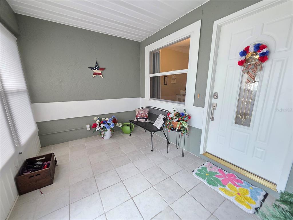A covered porch features tiled flooring, a metal bench, and a white front door — 2258 SILVER RE DRIVE, LAKELAND, FL