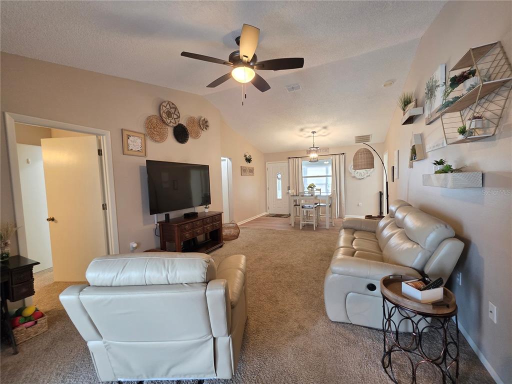 A living room with beige carpet, a leather sofa and chair, and a dining area — 2258 SILVER RE DRIVE, LAKELAND, FL
