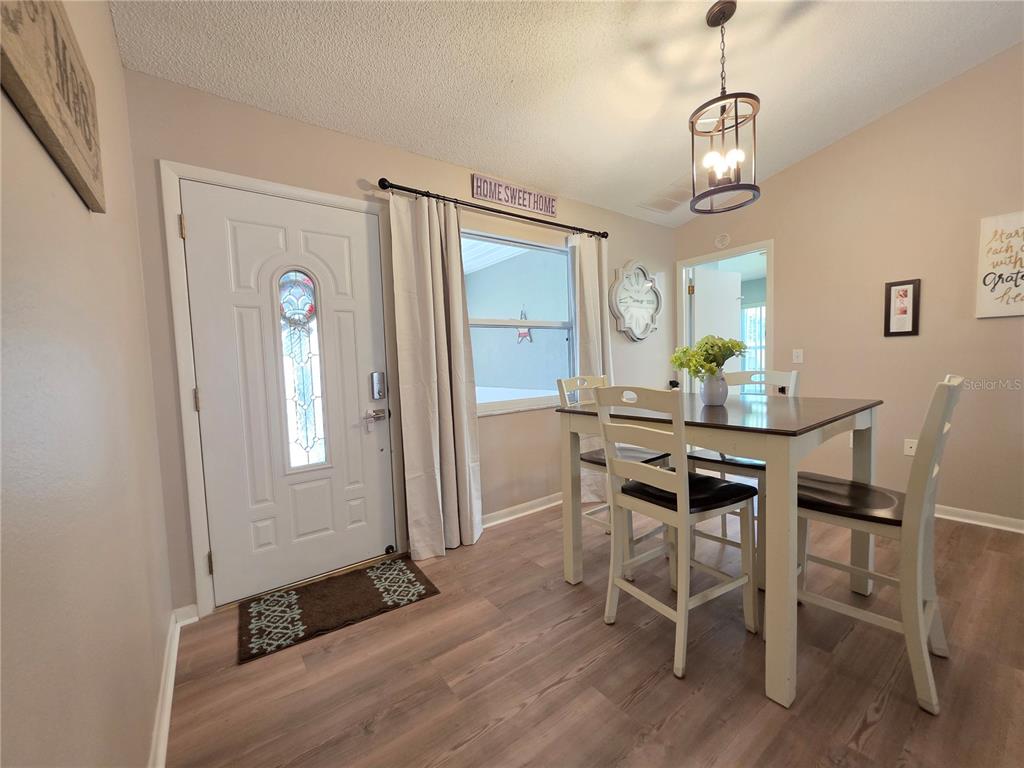 A dining area features a wooden table with chairs, light wood flooring, and a front door — 2258 SILVER RE DRIVE, LAKELAND, FL