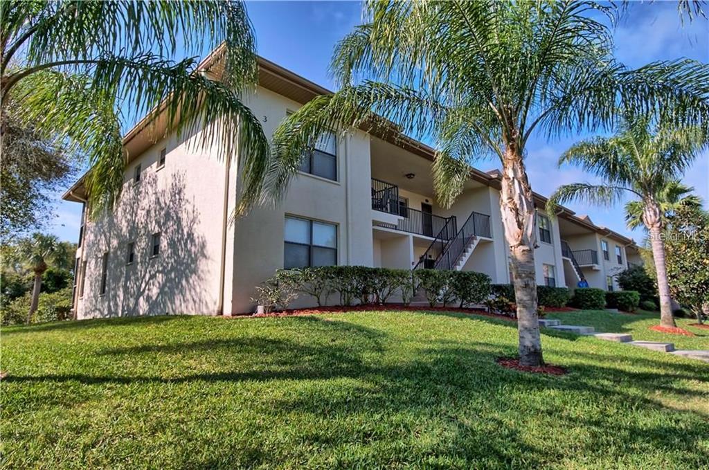 A two-story apartment building exterior features a staircase leading to an upper-level walkway — 1673 SEASCAPE CIRCLE UNIT 102, TARPON SPRINGS, FL