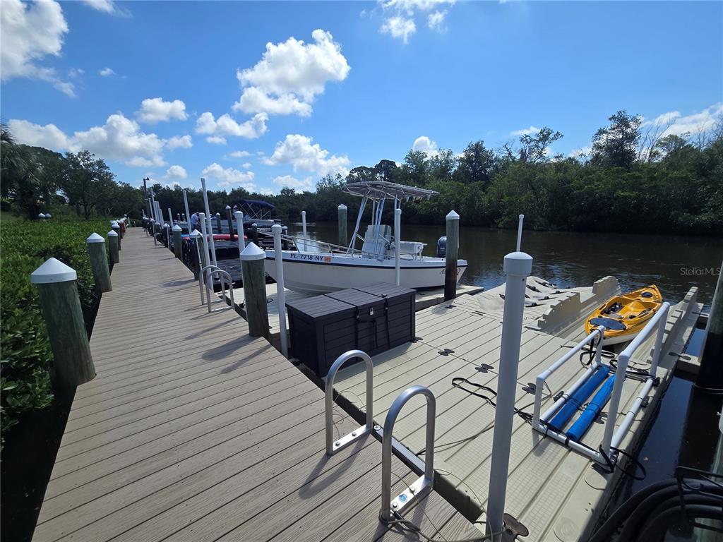 A wooden dock extends into a waterway with a boat, a kayak, and pilings — 1673 SEASCAPE CIRCLE UNIT 102, TARPON SPRINGS, FL