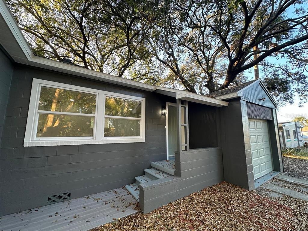 A gray concrete block house features a front porch, steps, and an attached garage — 2402 STEVENS AVENUE, SANFORD, FL
