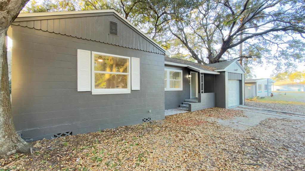 A gray, single-story concrete block house features white shutters, a small front porch, and a garage — 2402 STEVENS AVENUE, SANFORD, FL