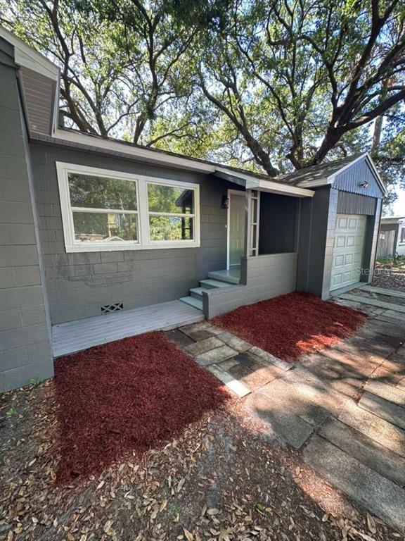A gray-painted concrete block house features a small front porch, steps, and an attached garage — 2402 STEVENS AVENUE, SANFORD, FL
