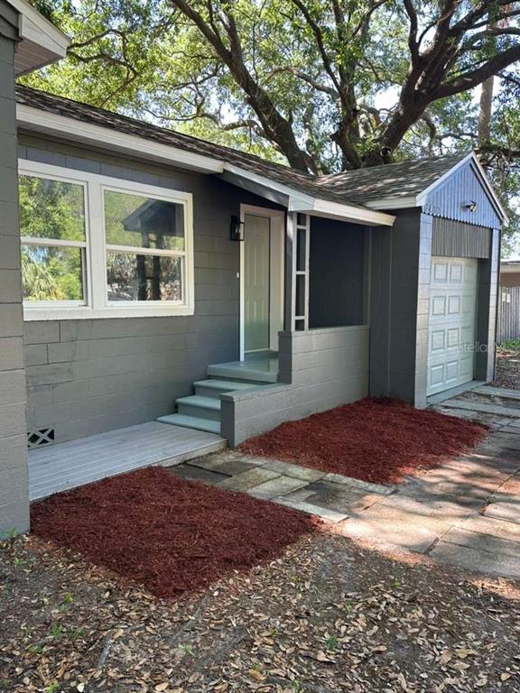 A gray house exterior features a front porch, steps, and a white garage door — 2402 STEVENS AVENUE, SANFORD, FL
