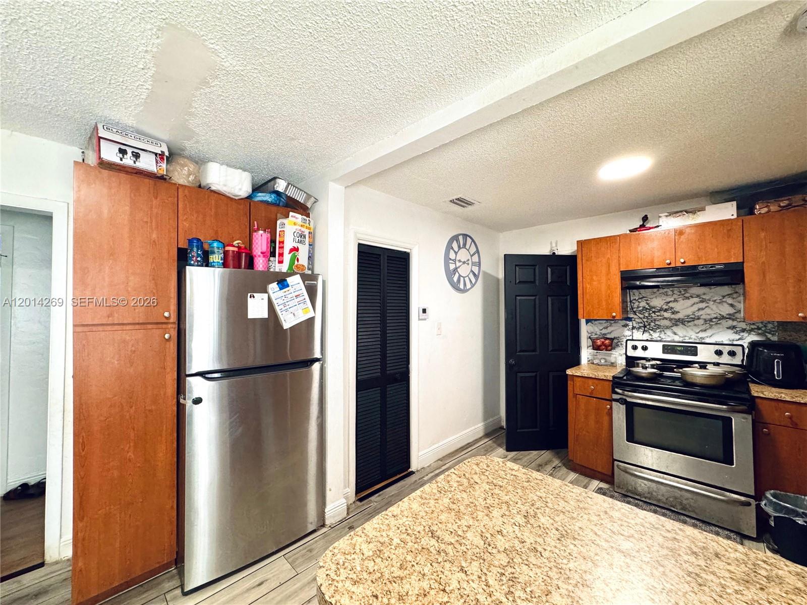 A kitchen features wood cabinets, stainless steel appliances, and a granite-topped island — 1484 NW 60th St, Miami FL 33142, MIAMI, FL