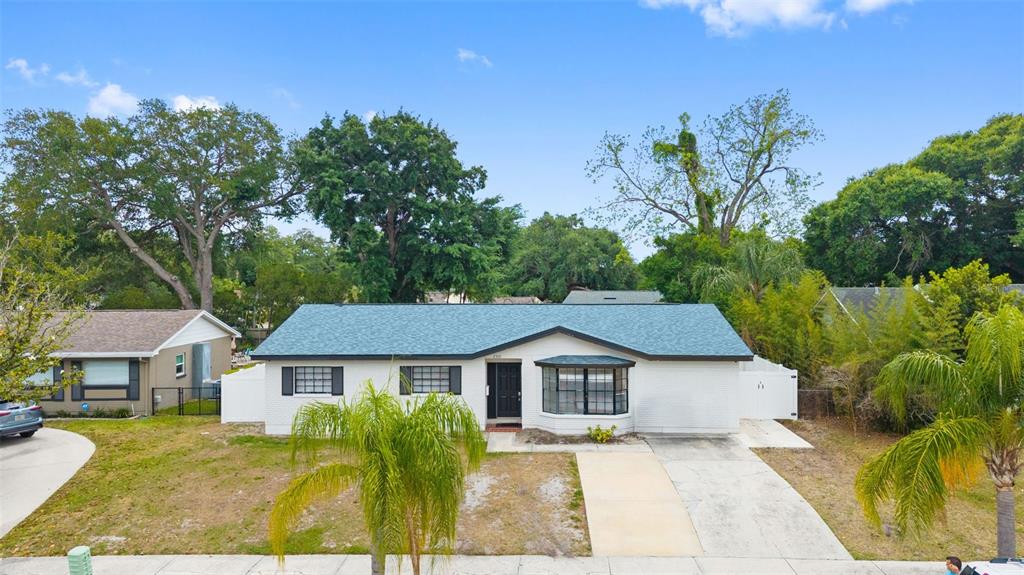 A single-story white brick house with a blue shingled roof and a front driveway — 2310 W KNOLLWOOD PLACE, TAMPA, FL