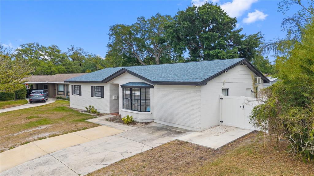 A white brick single-story house features a bay window and a white vinyl side gate — 2310 W KNOLLWOOD PLACE, TAMPA, FL