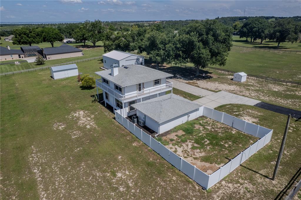 An aerial view shows a two-story white house with a fenced yard and detached garage — 13011 HIDDEN RIDGE LANE, CLERMONT, FL