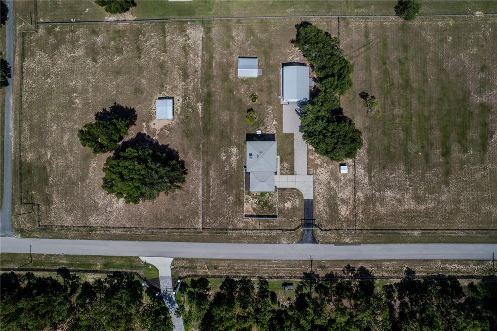 An aerial view shows a house, a detached garage, and two sheds on a fenced lot — 13011 HIDDEN RIDGE LANE, CLERMONT, FL