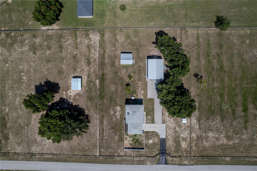 An aerial view shows a house, a detached garage, and two sheds on a fenced lot — 13011 HIDDEN RIDGE LANE, CLERMONT, FL