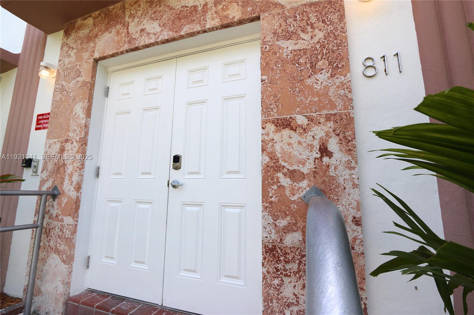 A white double door with a digital lock is set into a textured stone wall — 811 Jefferson Ave # 105, Miami Beach FL 33139, MIAMI BEACH, FL