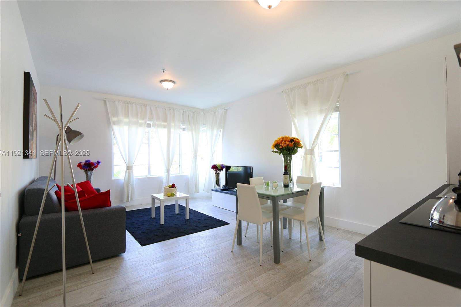 A living and dining area features white walls, light wood floors, and sheer curtains — 811 Jefferson Ave # 105, Miami Beach FL 33139, MIAMI BEACH, FL