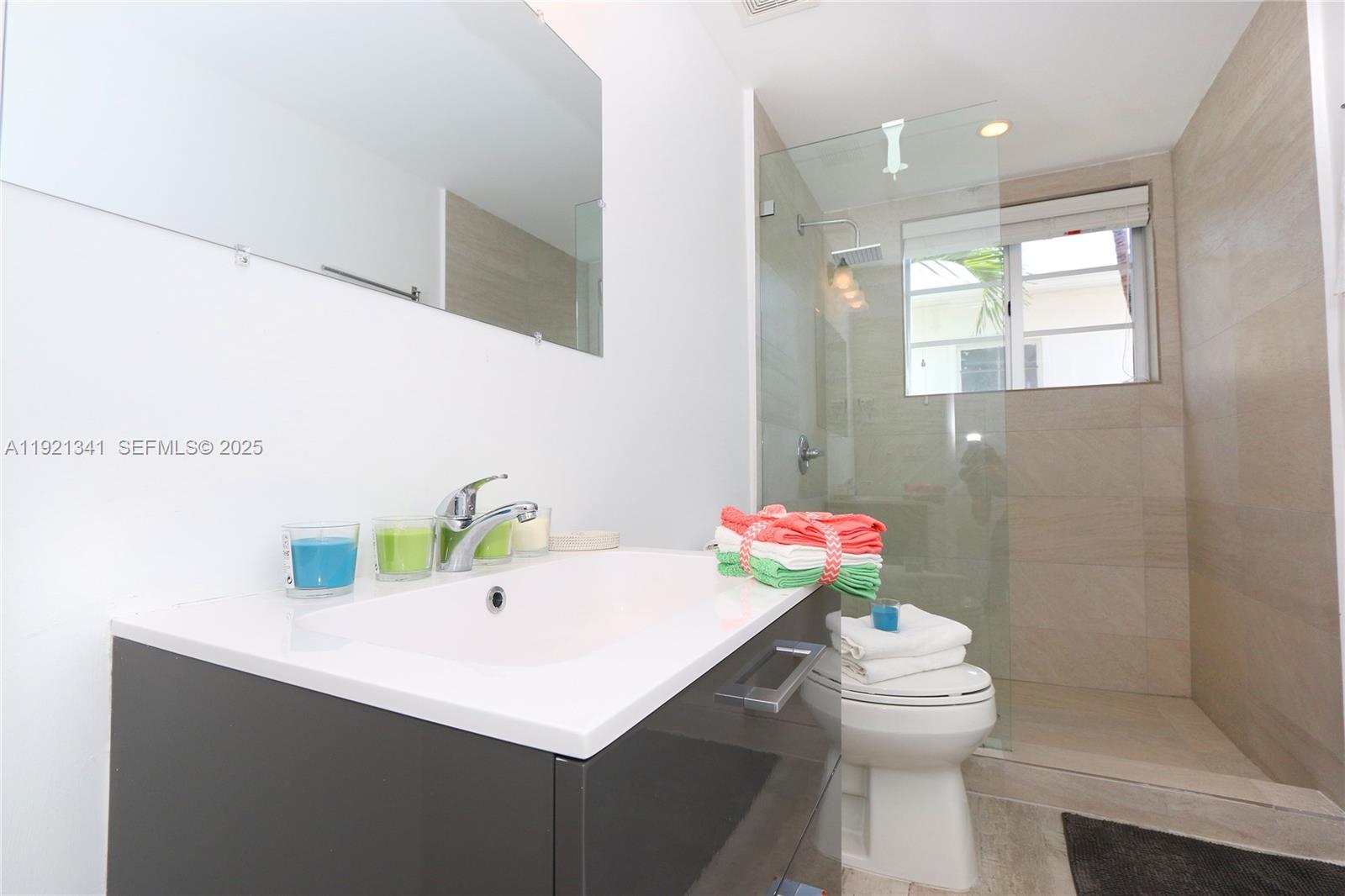 A modern bathroom features a vanity, a glass-enclosed shower, and a toilet — 811 Jefferson Ave # 105, Miami Beach FL 33139, MIAMI BEACH, FL