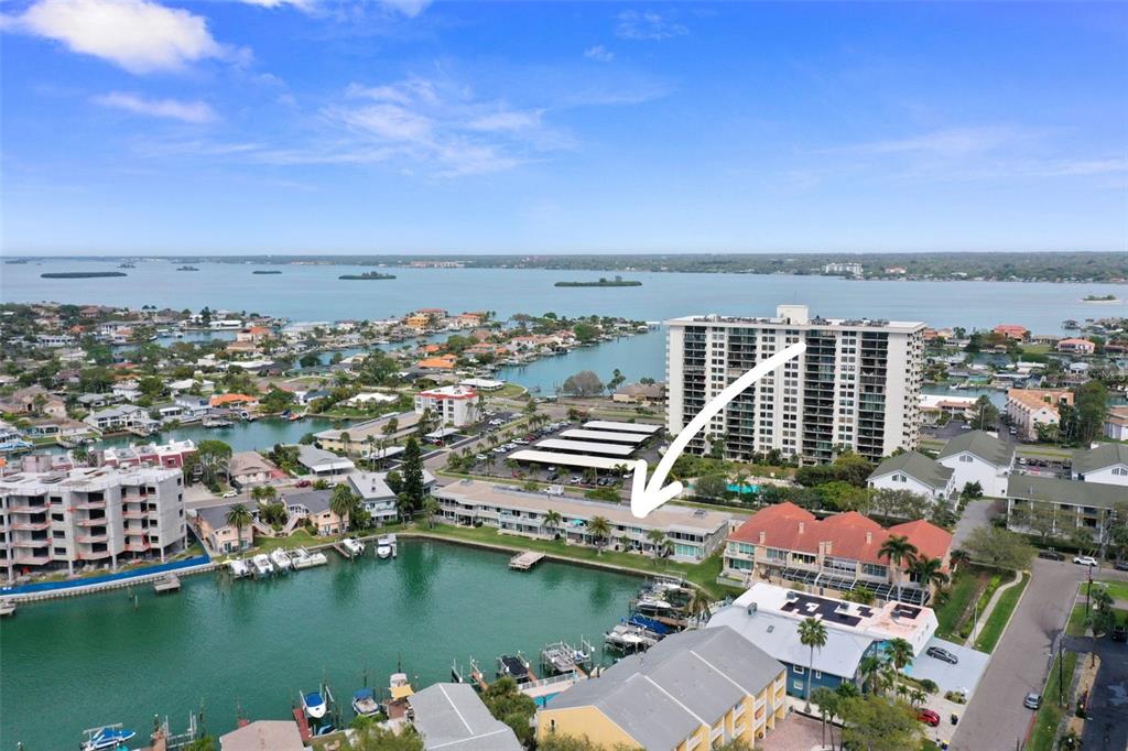 An aerial view shows a waterfront apartment complex with a boat dock and swimming pool — 400 LARBOARD WAY UNIT 103, CLEARWATER BEACH, FL