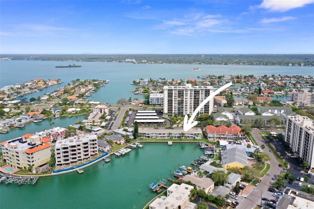 An aerial view shows a waterfront condominium complex with a boat dock and parking — 400 LARBOARD WAY UNIT 103, CLEARWATER BEACH, FL