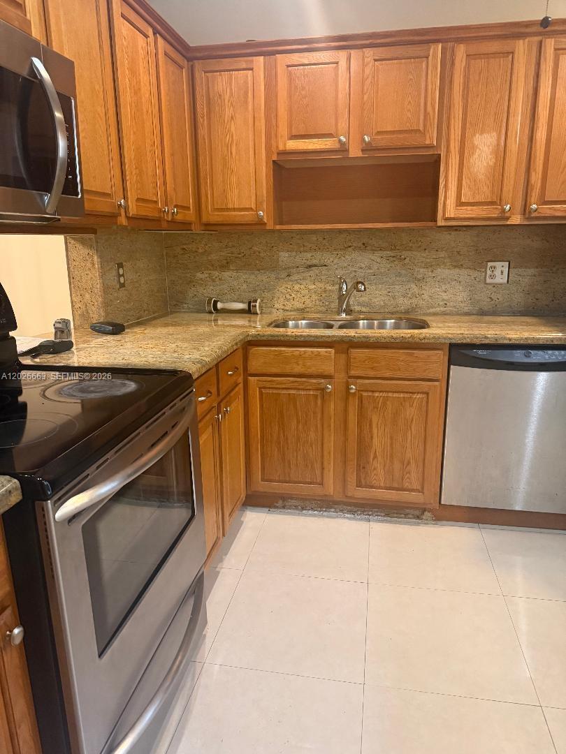 A kitchen features oak cabinets, granite countertops, and stainless steel appliances — 100 Ashbury Rd # 104, Hollywood FL 33024, HOLLYWOOD, FL